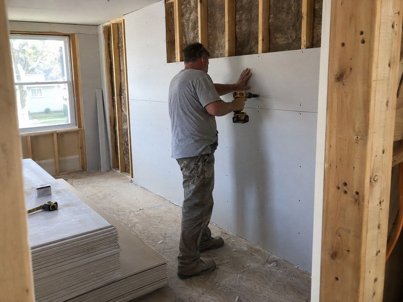 Illustration of a worker fastening drywall during a home renovation